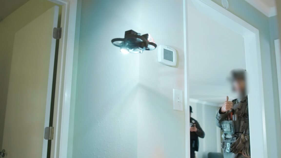 Police drone equipped with a magnet hovers over a motionless suspect, preparing to lift a knife.