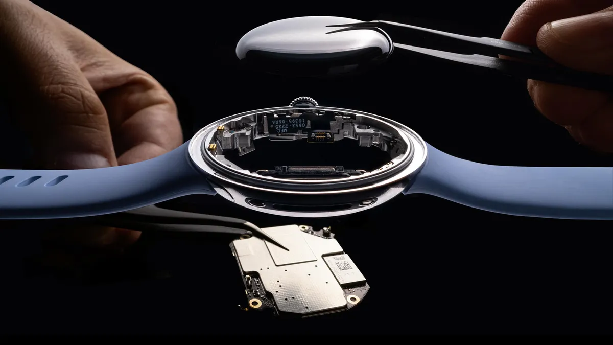 Close-up of a person's hand holding a disassembled smartwatch, showing the battery compartment.