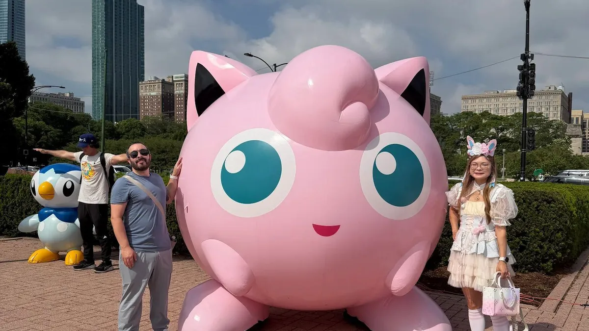 A large crowd of people playing Pokémon Go at a festival, with many families present.